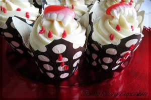 cupcakes de halloween decorados con colmillos plasticos de vampito y glaseado de color rojo